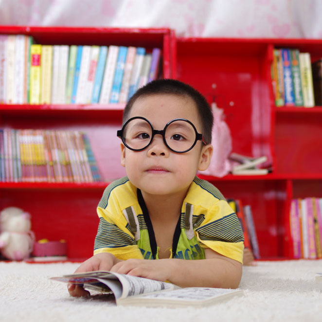 Asian child with glasses reading comic book
