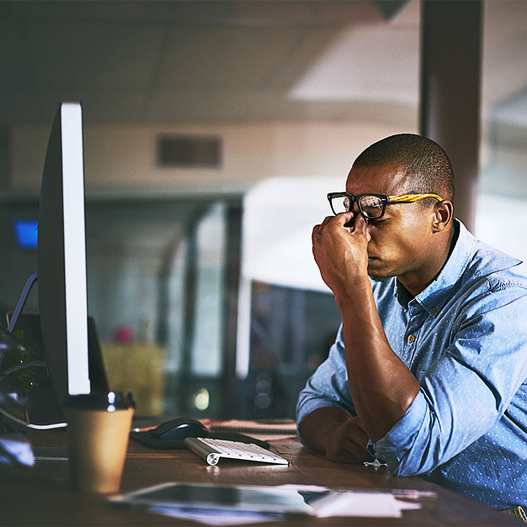 Employee with glasses at computer experiencing eyestrain