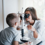 Female optometrist giving child an eye exam