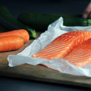 Uncooked salmon next to some vegetables