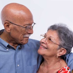 Older couple wearing glasses while smiling at each other