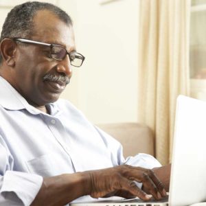 Black man wearing glasses while using a laptop