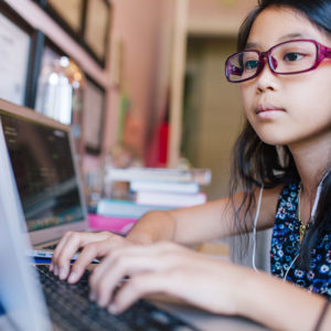 Young girl doing school work on laptop