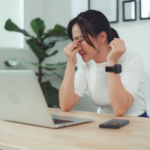 Woman rubbing her eyes while working