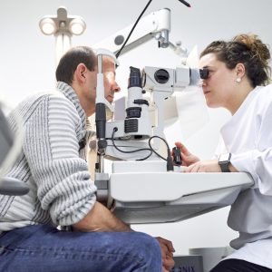Female ophthalmologist examining male patient in ophthalmology clinic with autorefractometer, examination of eyesight