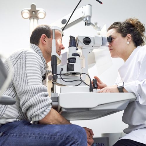 Female ophthalmologist examining male patient in ophthalmology clinic with autorefractometer, examination of eyesight
