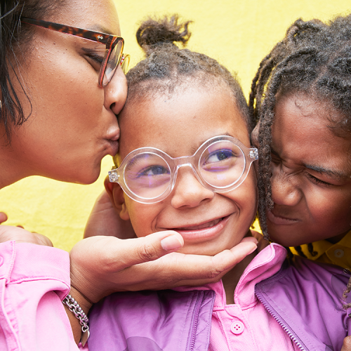 Family embracing young child wearing glasses