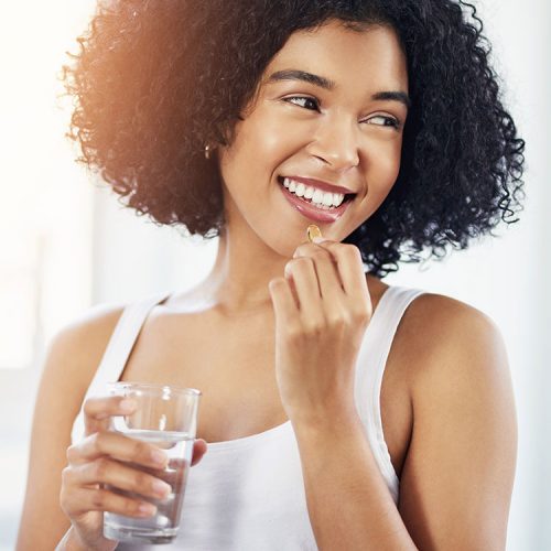 Young woman taking fish oil supplement